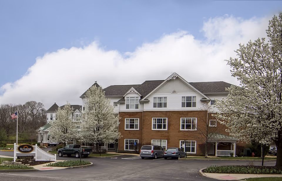 Exterior view of Sunrise of Chesterfield building with blooming trees and parked cars.