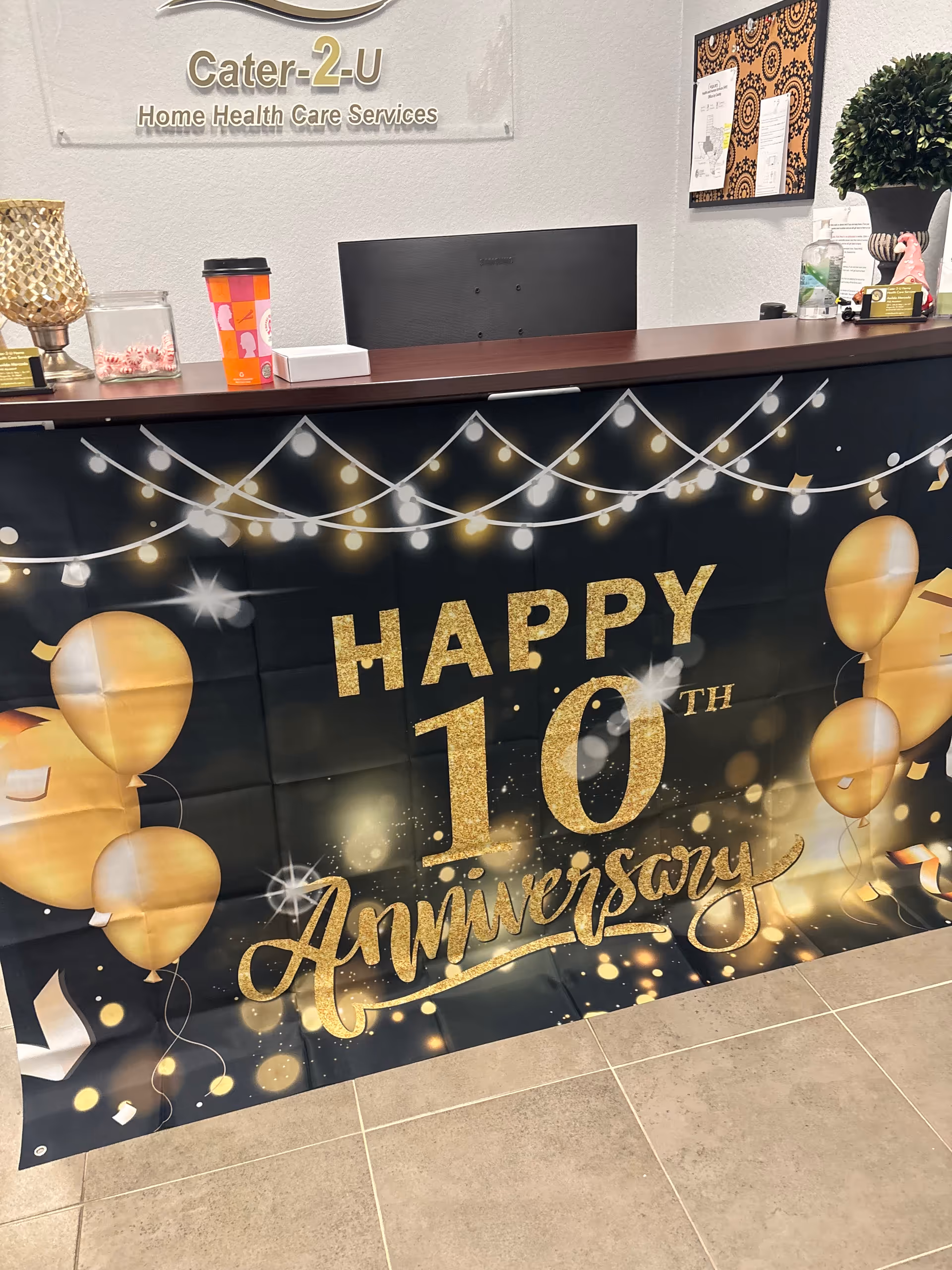Reception desk inside a facility with Cater-2-U Home Health Care Services sign and 10th anniversary banner.