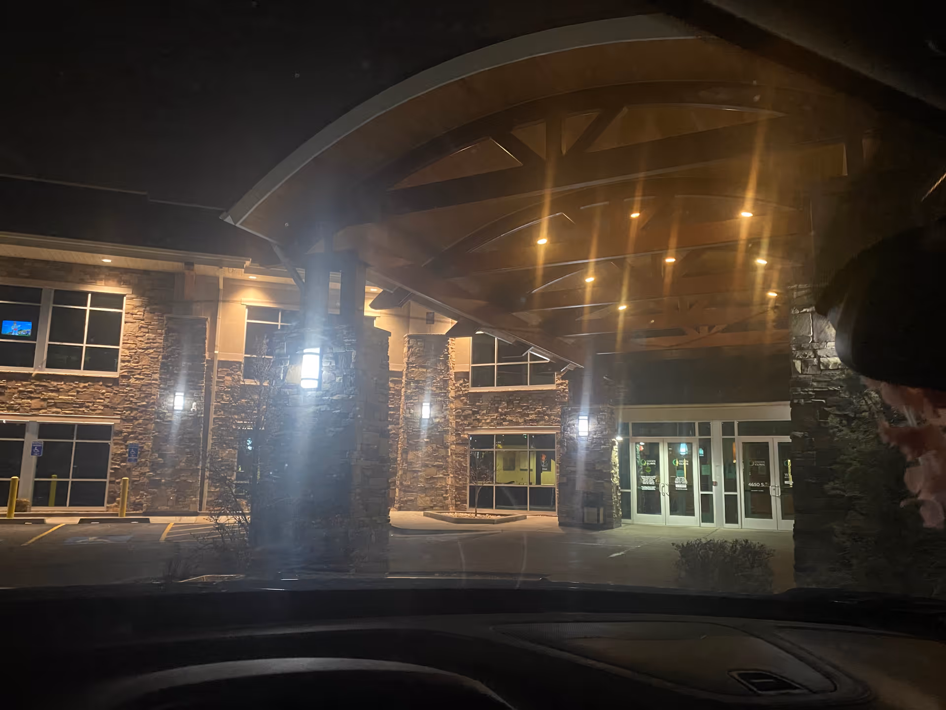 Night exterior of a stone-front building with a lit covered entrance.