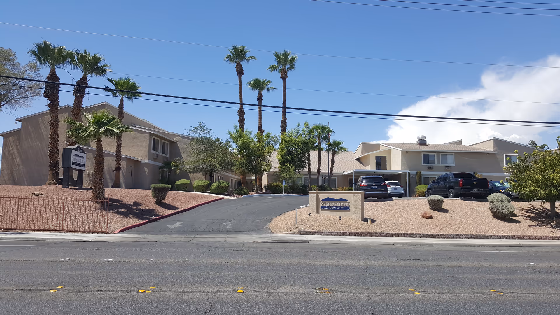 Exterior view of Sterling Ridge Senior Living with palm trees, driveways, and parked cars.