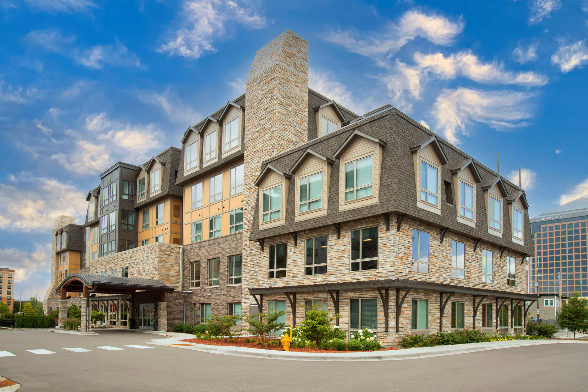 Front view of a multi-story stone-and-wood senior living facility.