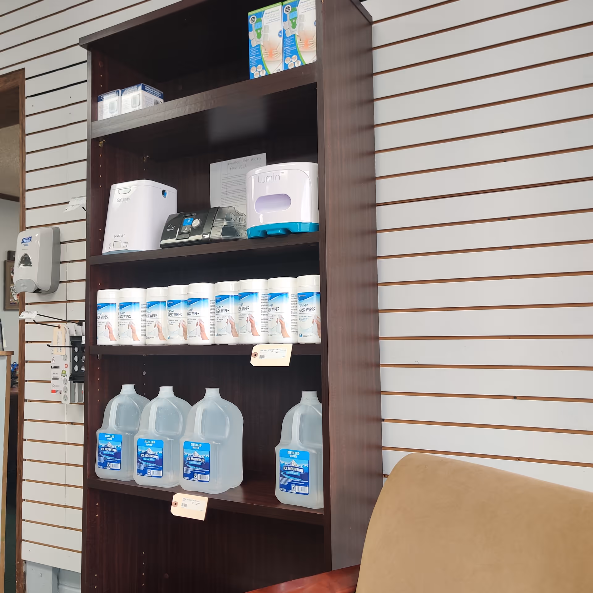 Tall wooden shelving unit displays medical supplies and devices in a slat-walled interior.