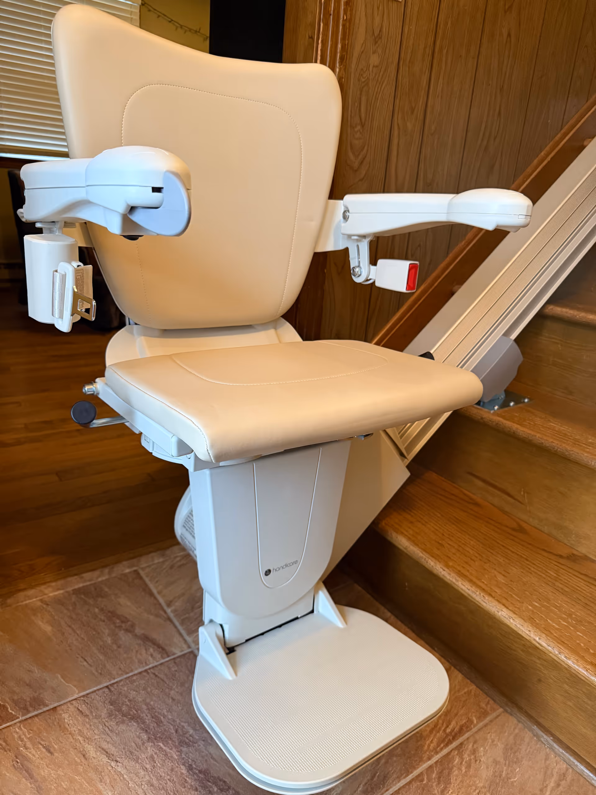 White stairlift chair beside wooden stairs in a cozy interior.