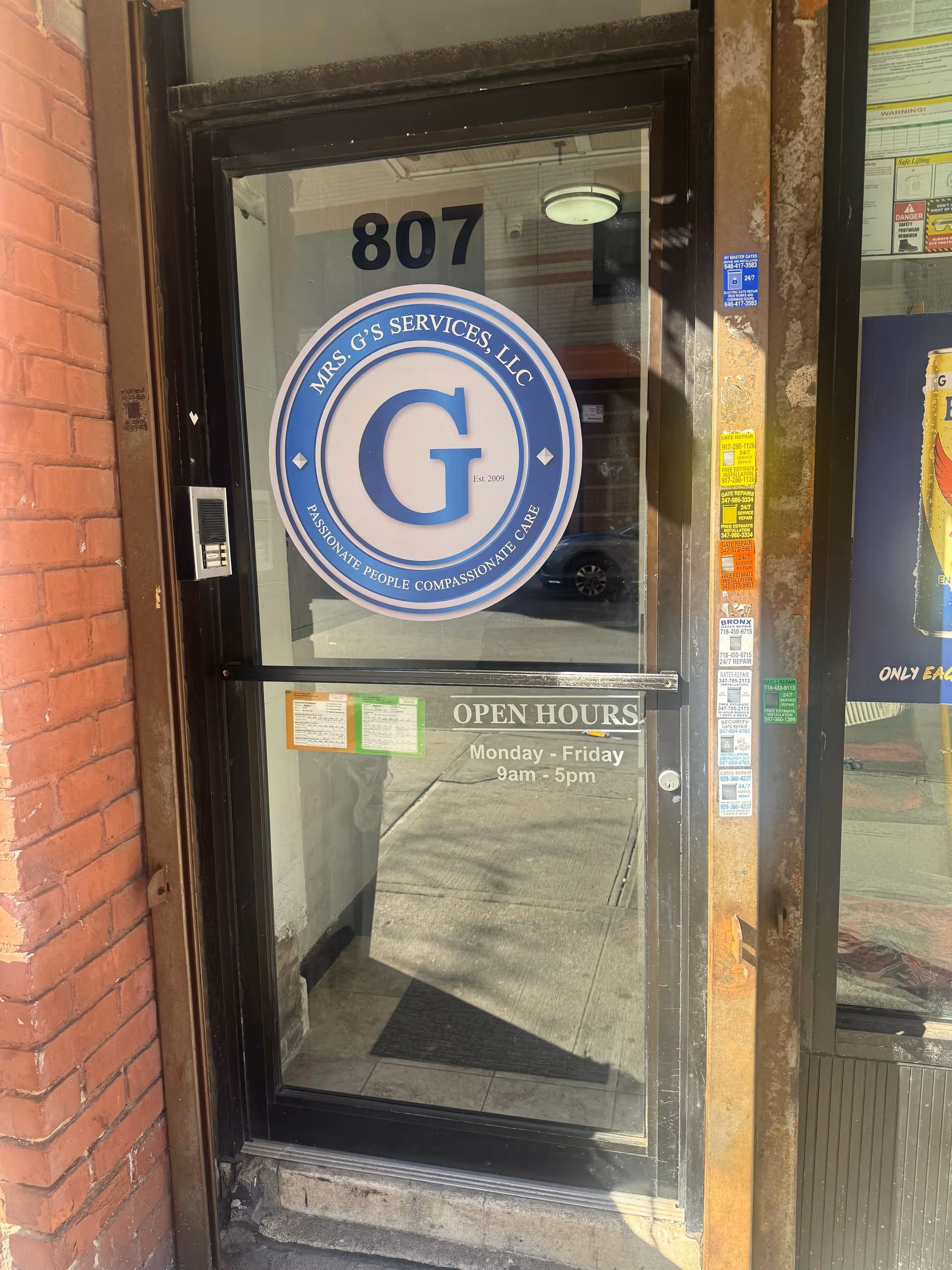 Glass door with MRS. G'S SERVICES LLC logo and open hours, storefront brick exterior