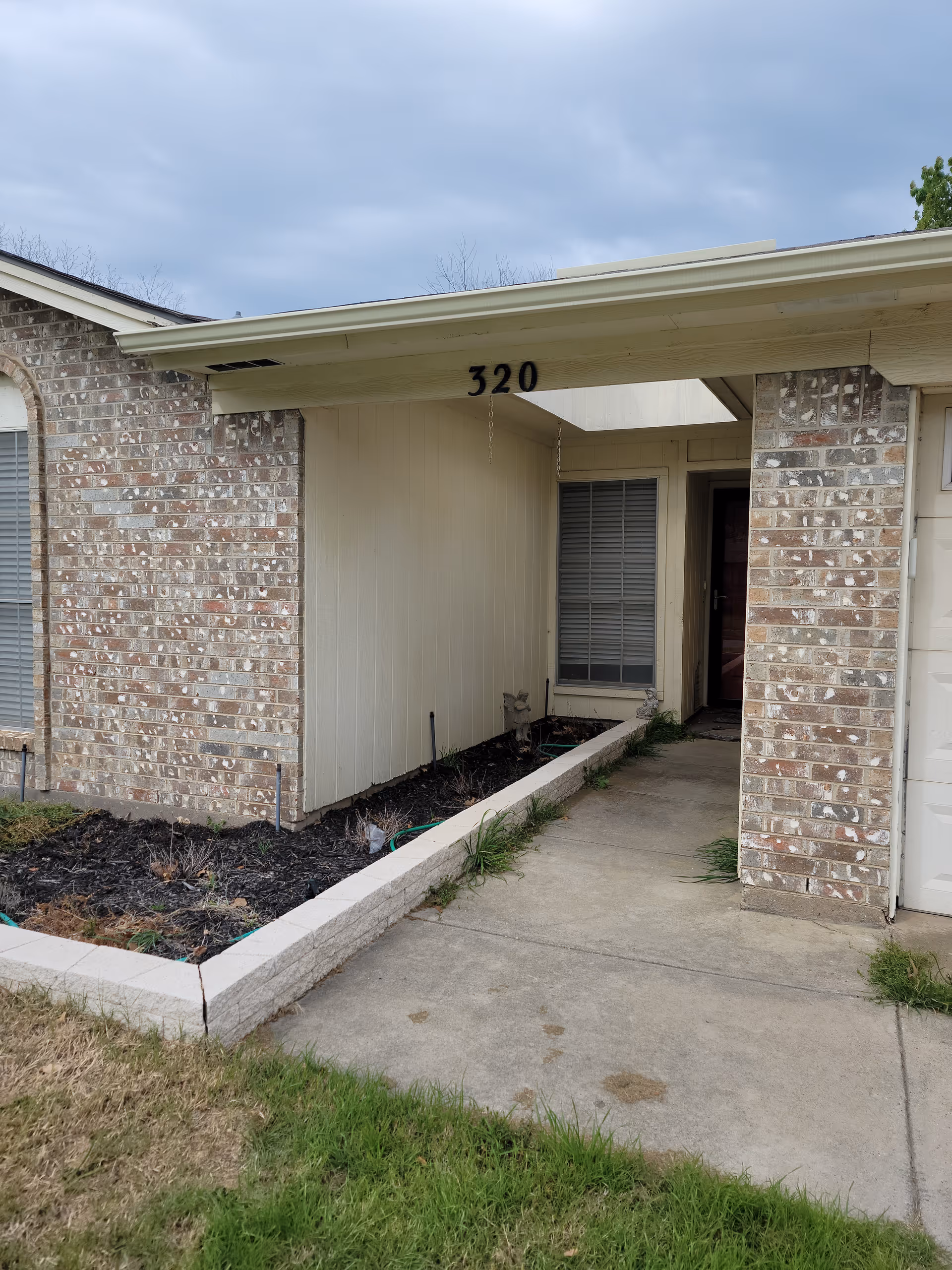 Exterior view of a brick senior living facility entrance with a walkway and address 320.