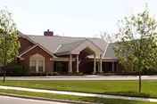 Front exterior of a single-story brick senior living center with a covered entrance.
