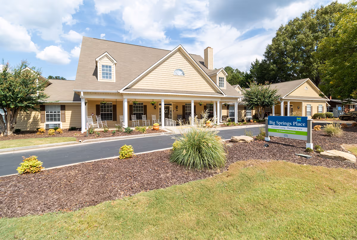 Single-story assisted living facility with beige siding, front porch, and a sign reading Big Springs Place.