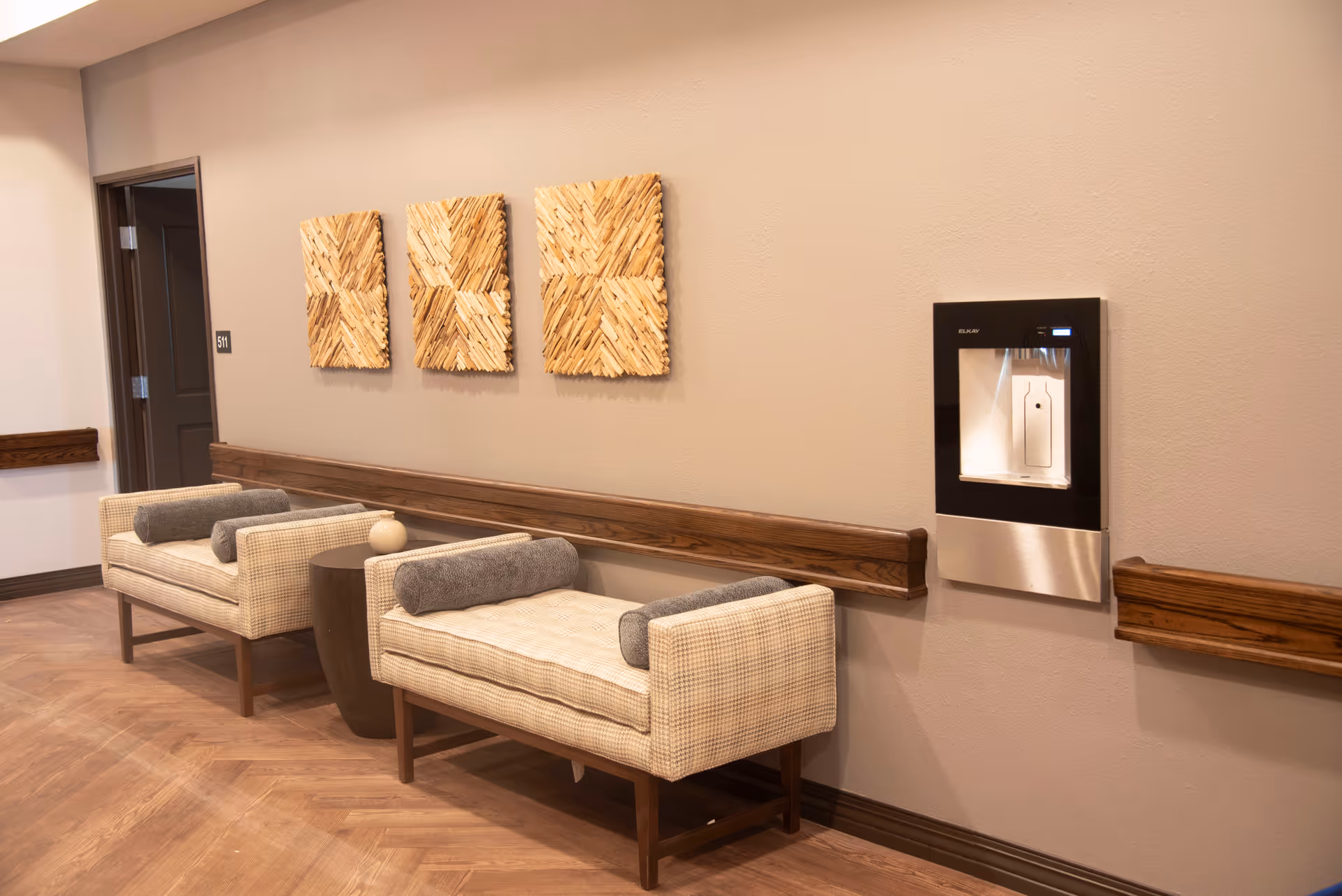 Hallway seating area with two beige plaid chairs, wood trim, and abstract wall art.