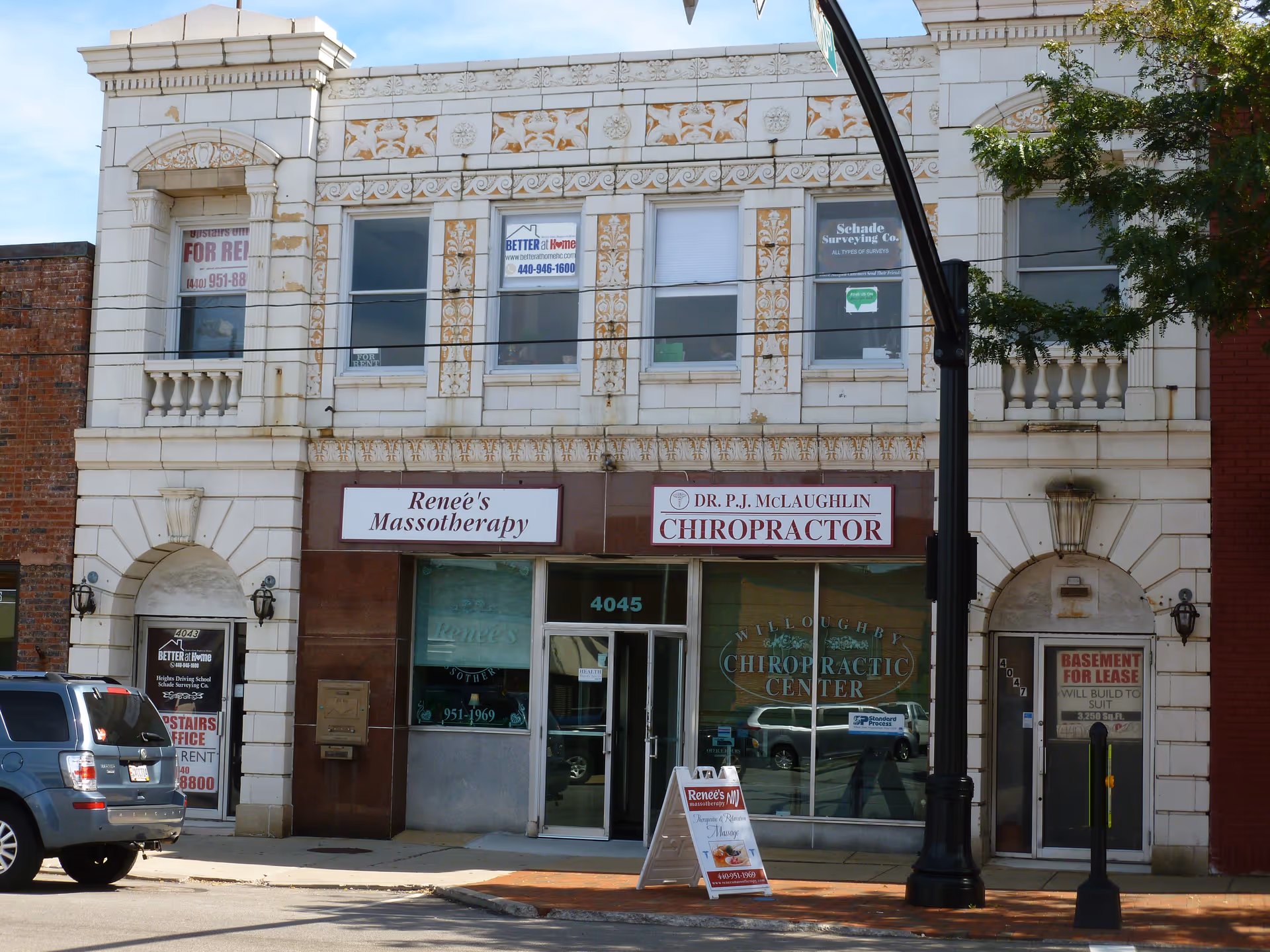 Urban building facade with multiple storefronts and chiropractor signage on the ground level.