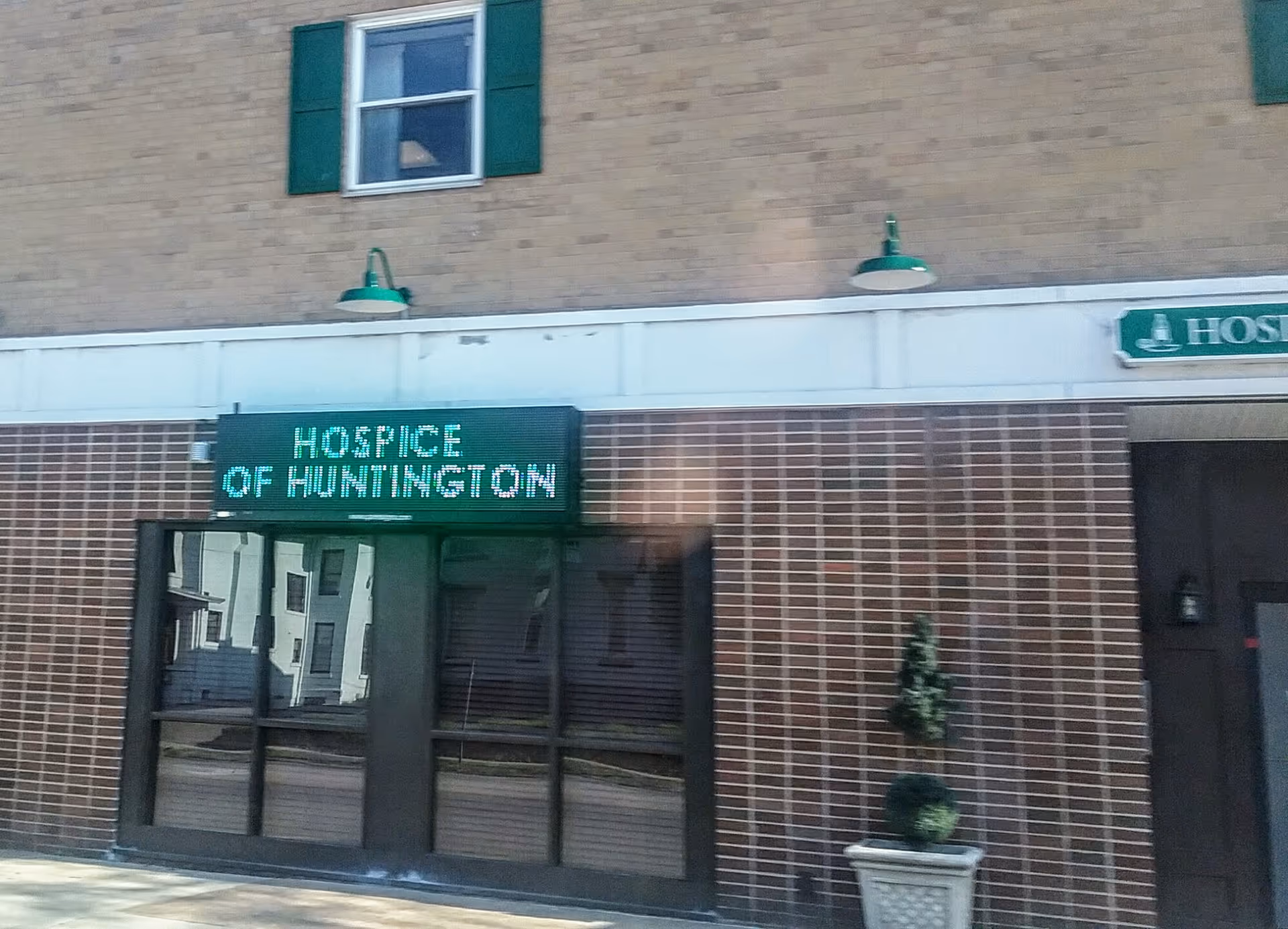 Exterior view of Hospice of Huntington entrance with brick facade and digital sign