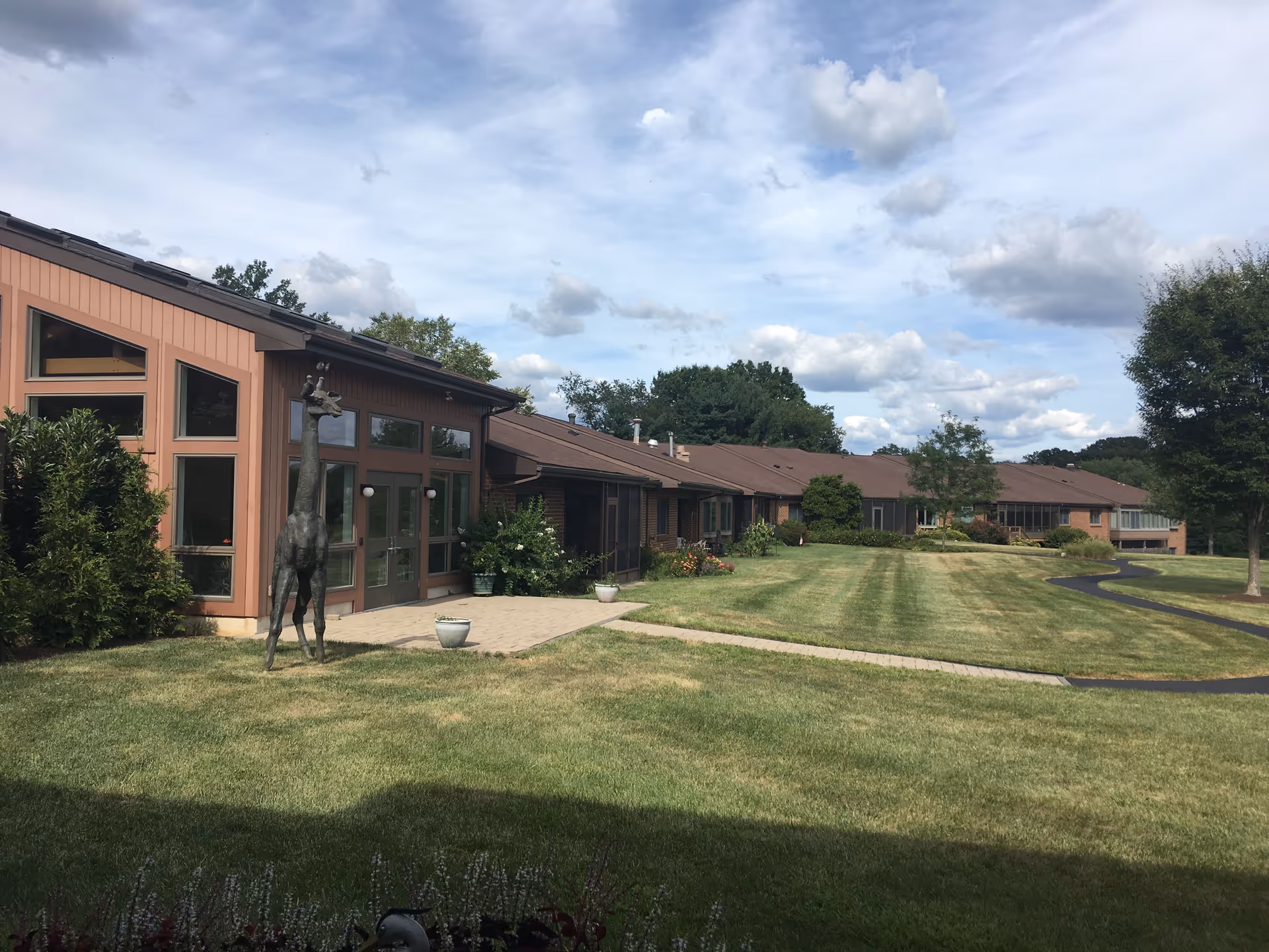 Exterior view of Cairnwood Village with brown building facade, walkway, and landscaped lawn