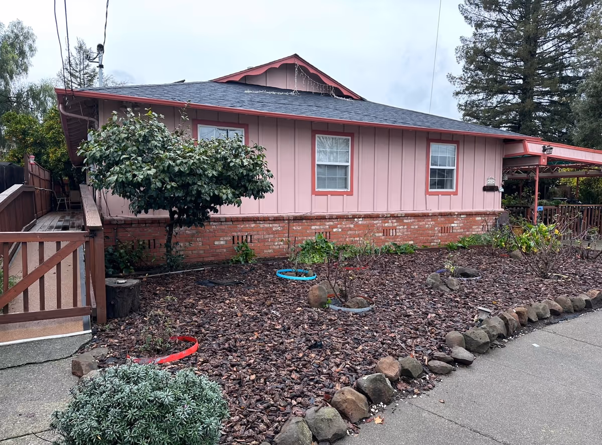 Pink, single-story building with brick base and mulched front yard.