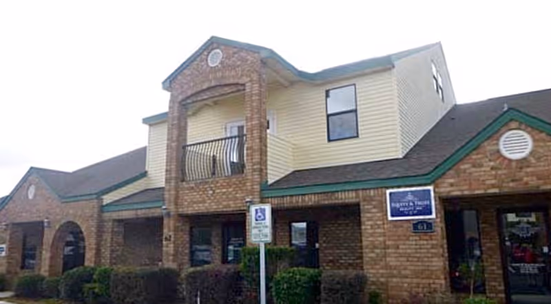 Exterior view of a beige brick senior living facility with signage and wheelchair parking.
