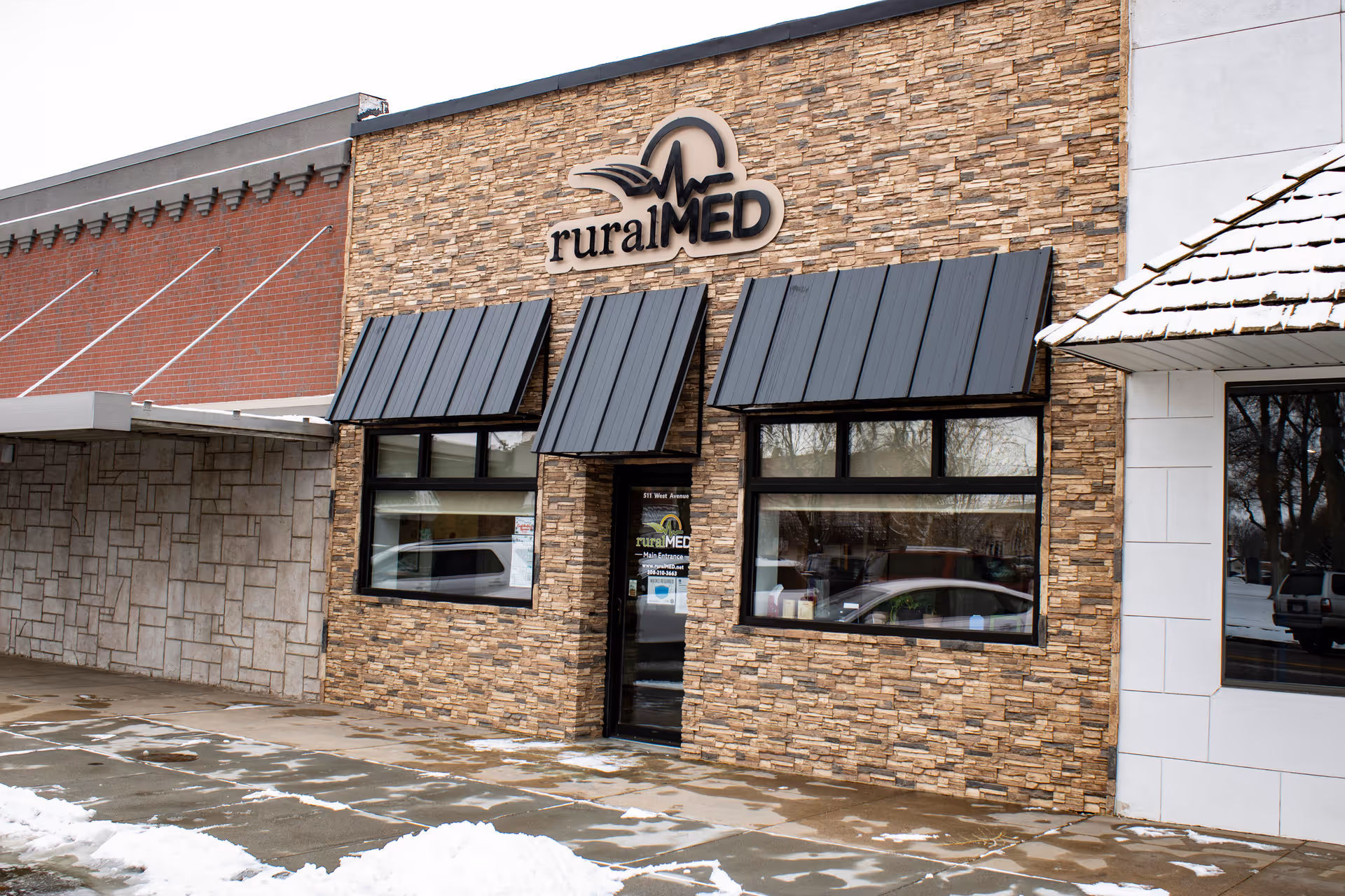 Exterior view of ruralMED Management Resources storefront with stone facade and snow.