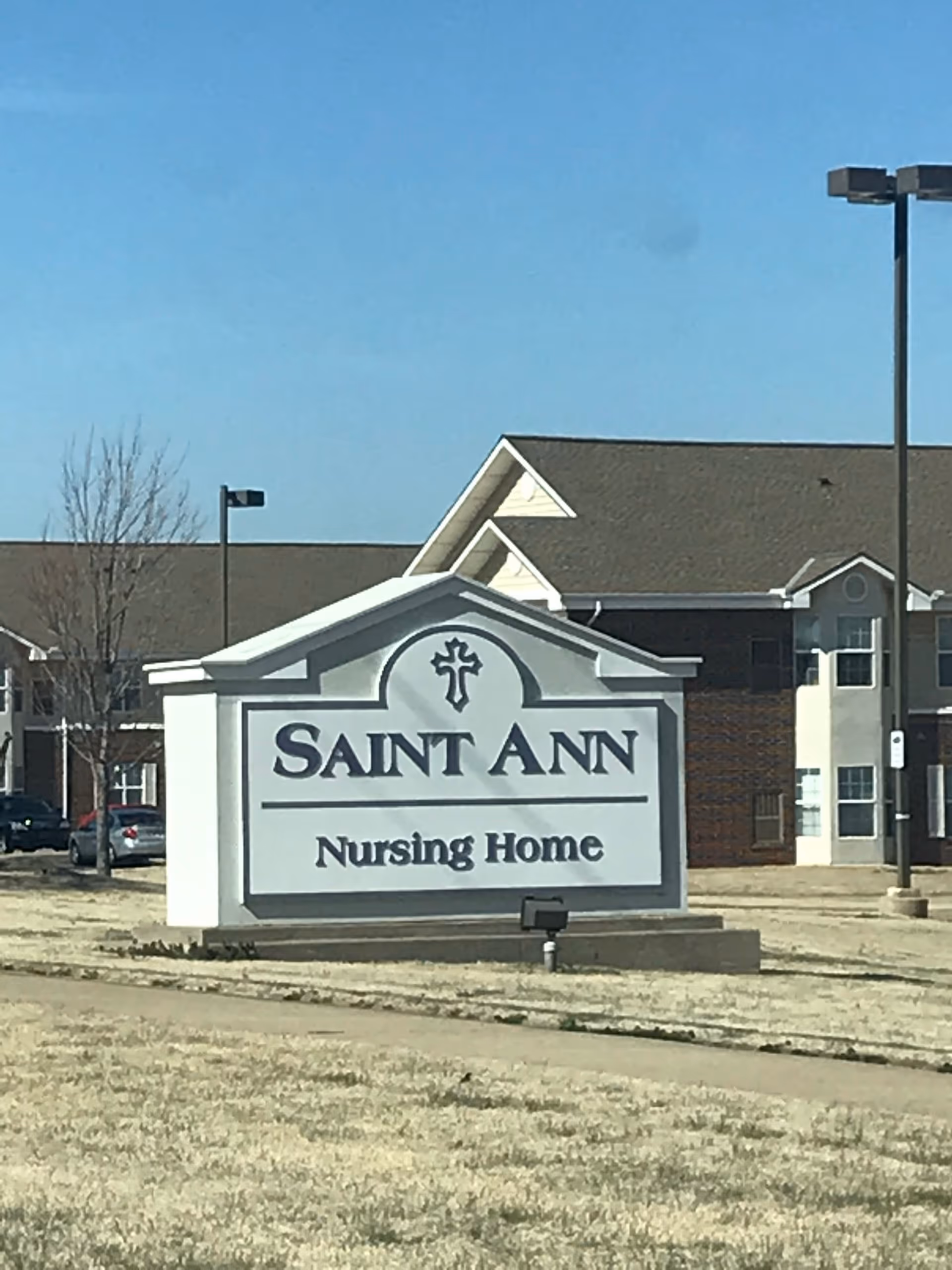 Large front-facing sign reading Saint Ann Nursing Home sits before a brick building.