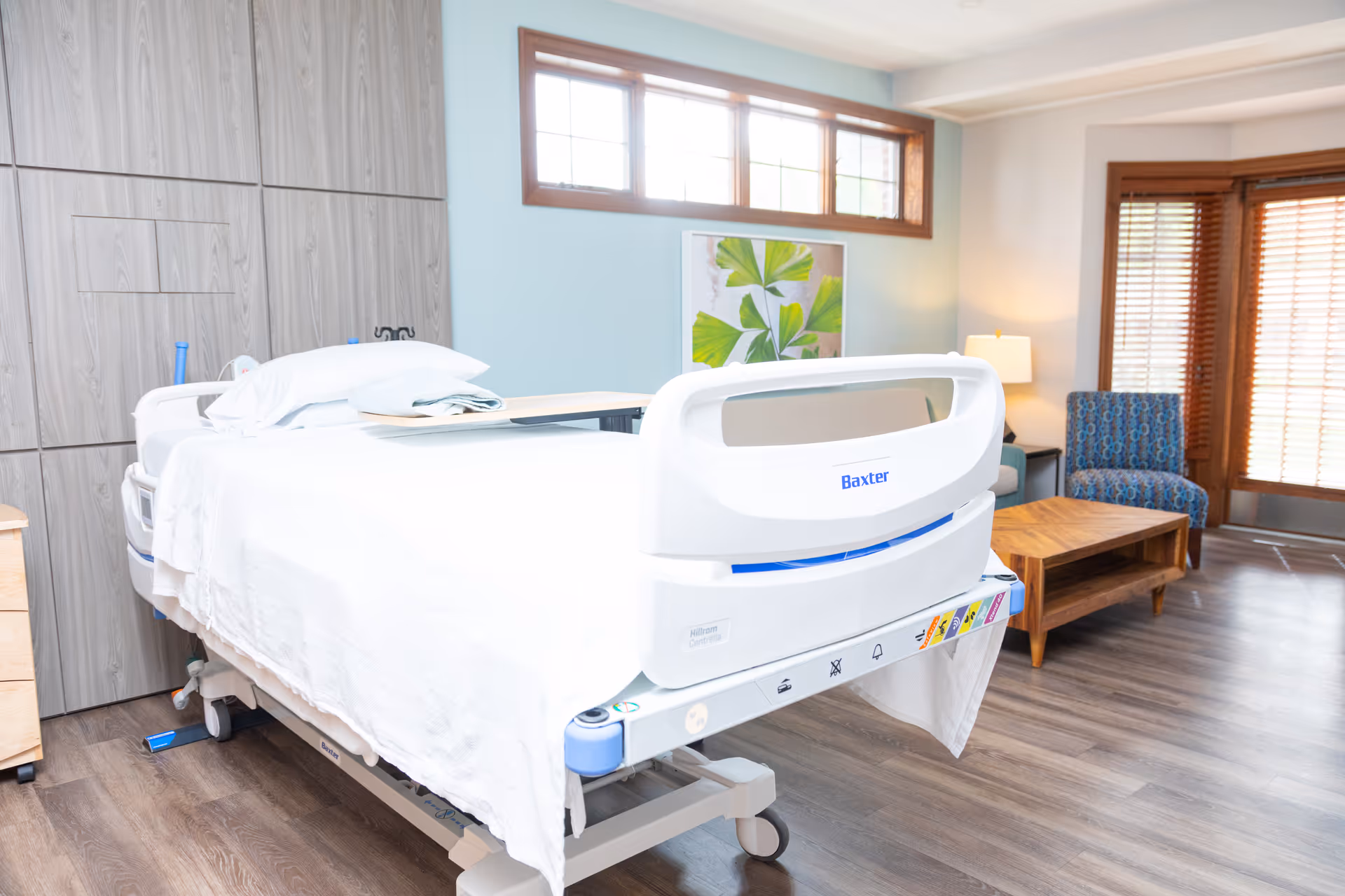 Hospice bedroom with a hospital bed and seating in a bright room.