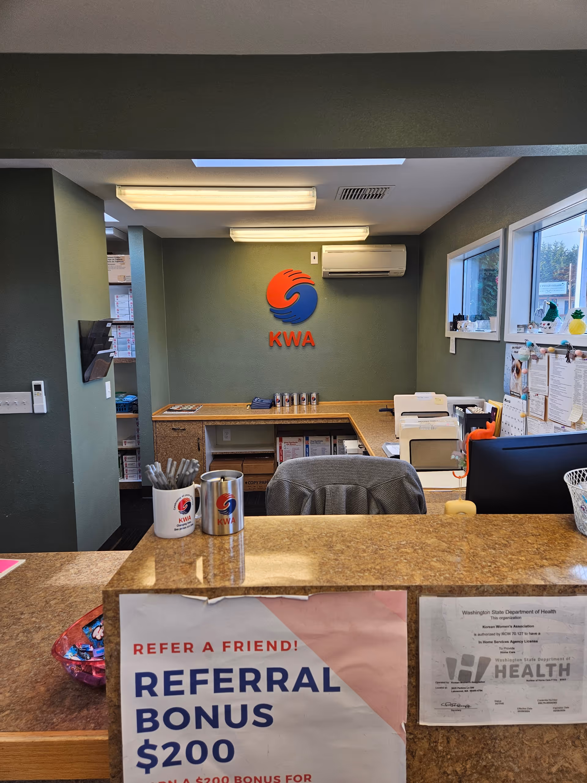 Reception desk in a green-walled office featuring the KWA logo and office signage.