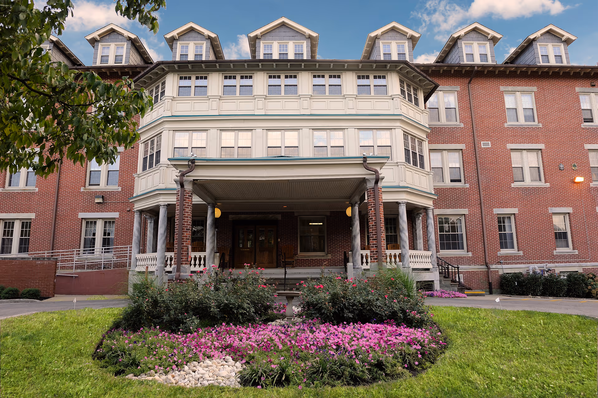 Brick Wesley Enhanced Living at Stapeley building with a covered entrance and flower beds.