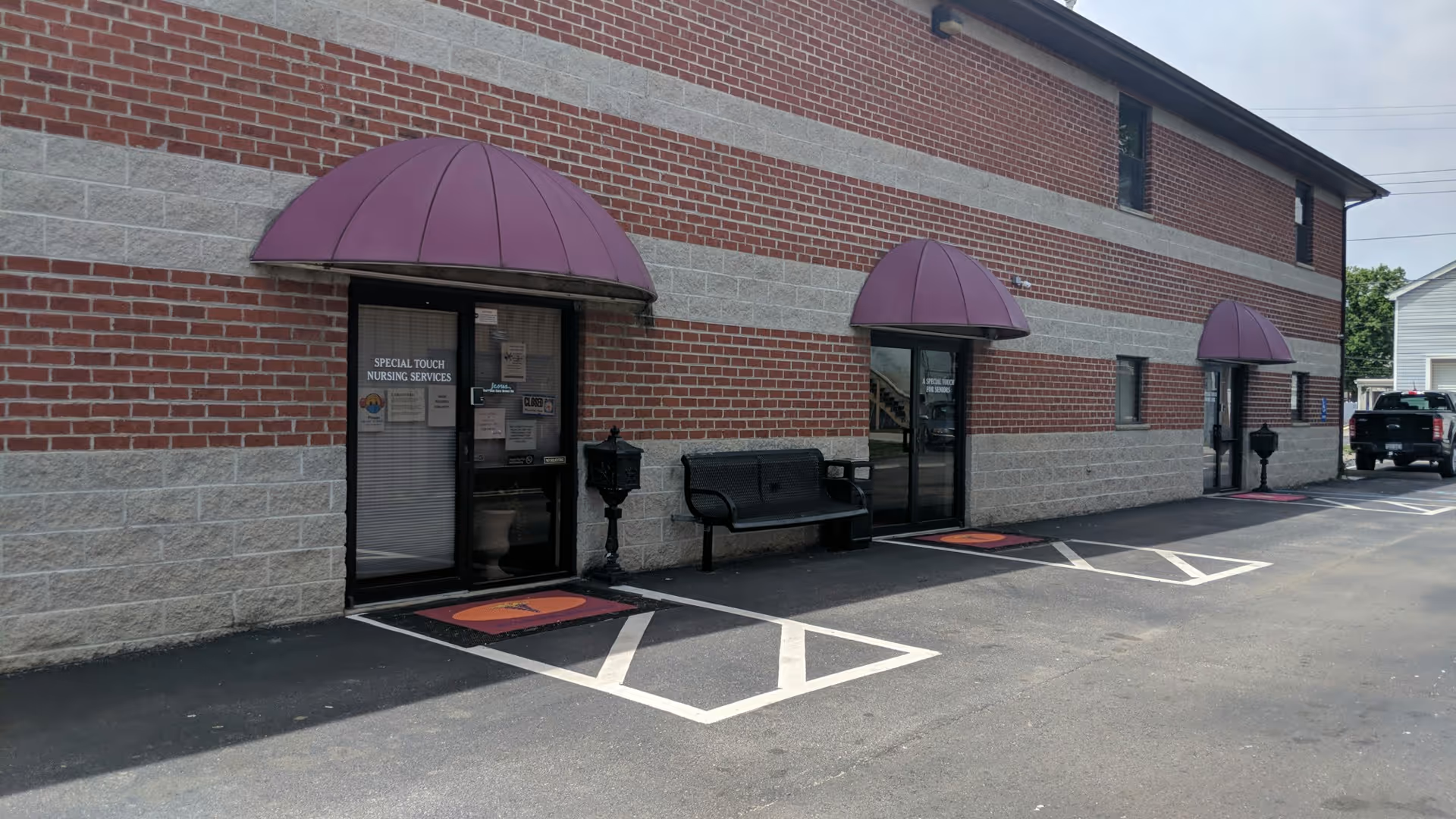 Brick building exterior of a nursing facility with purple awnings and entrances