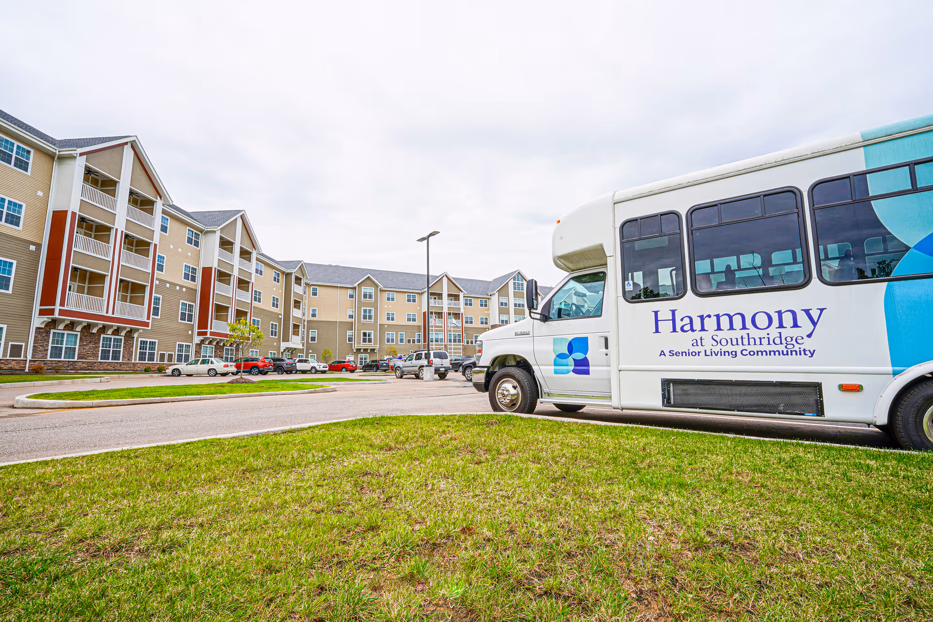 Exterior view of Harmony at Southridge senior living campus with a bus in the foreground