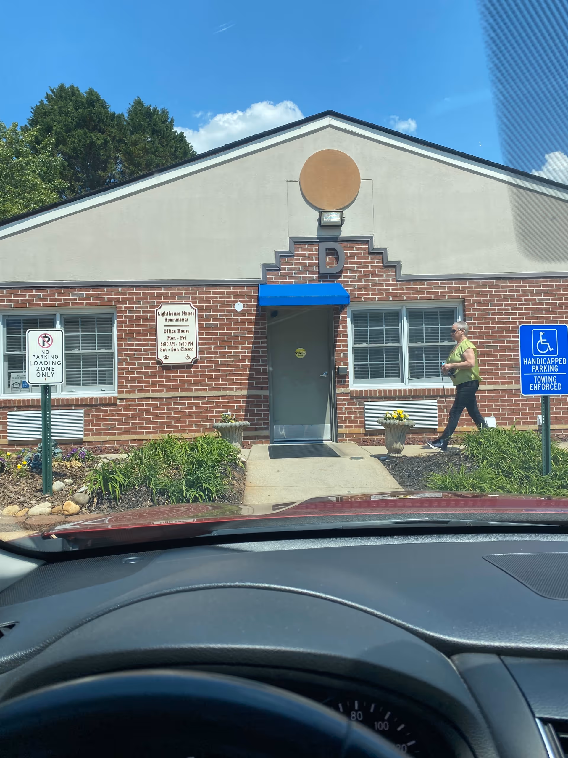 Lighthouse Manor exterior entrance with blue awning and a person walking nearby.