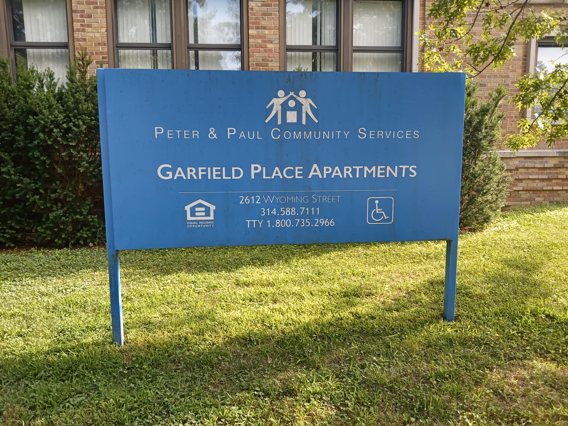 Blue Garfield Place Apartments sign in front of a brick building on a grassy lawn.