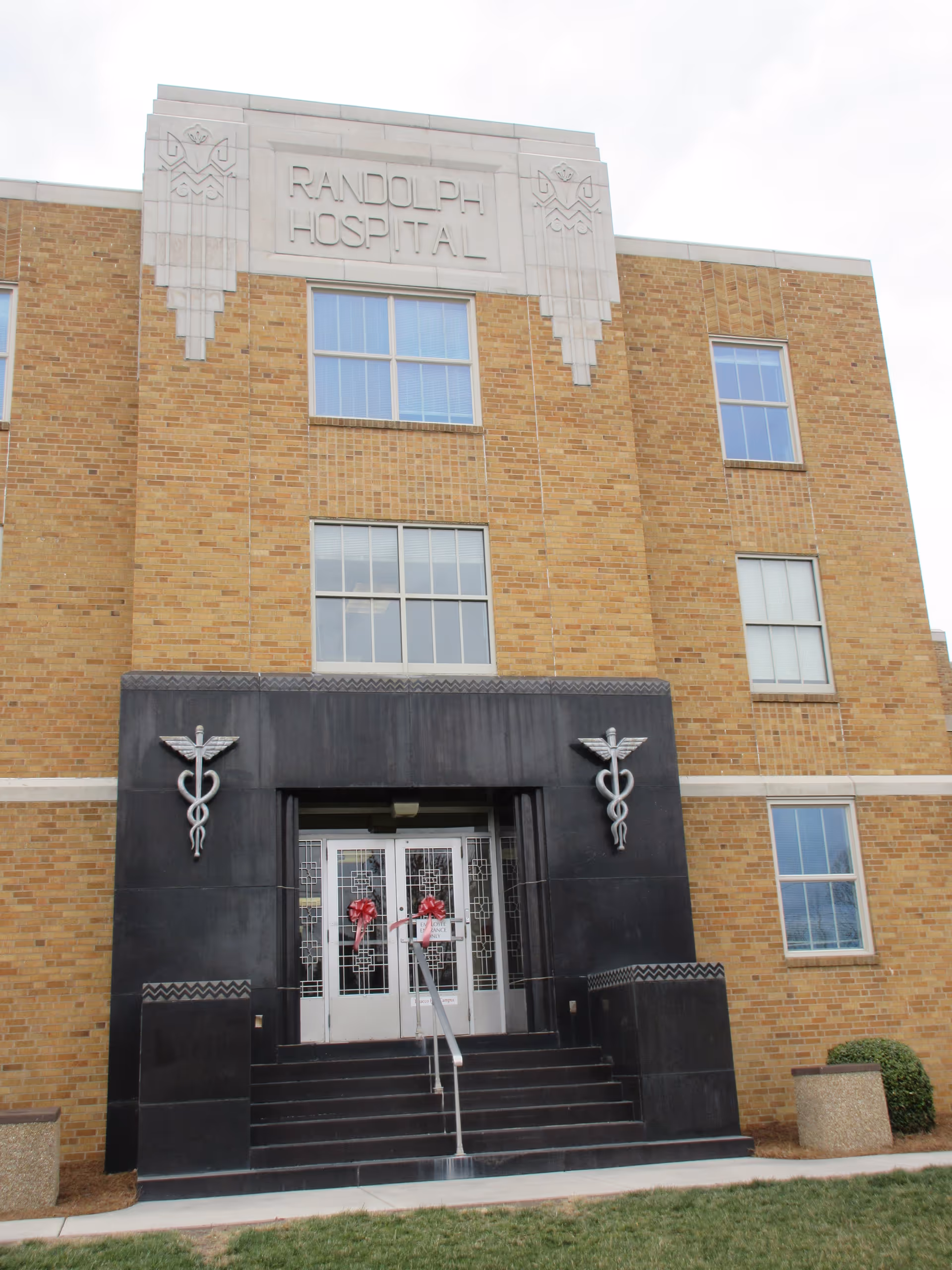 Brick hospital exterior with black entrance and double doors labeled Randolph Hospital