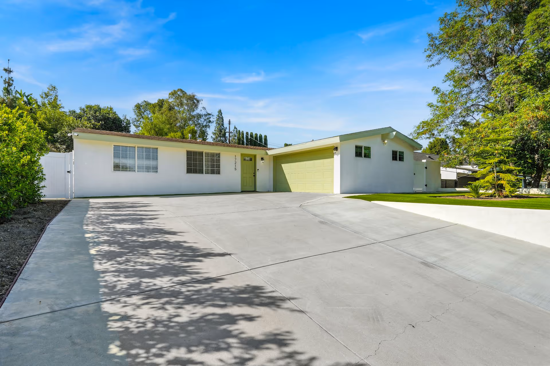 White single-story facility with a pale green garage door, driveway, and green lawn.