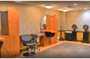 Nursing home hair salon with styling chairs, mirrors, sinks, and hairdryers along walls.