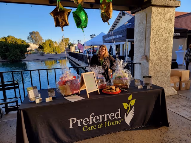 Outdoor waterfront booth with a Preferred Care at Home table and balloons.