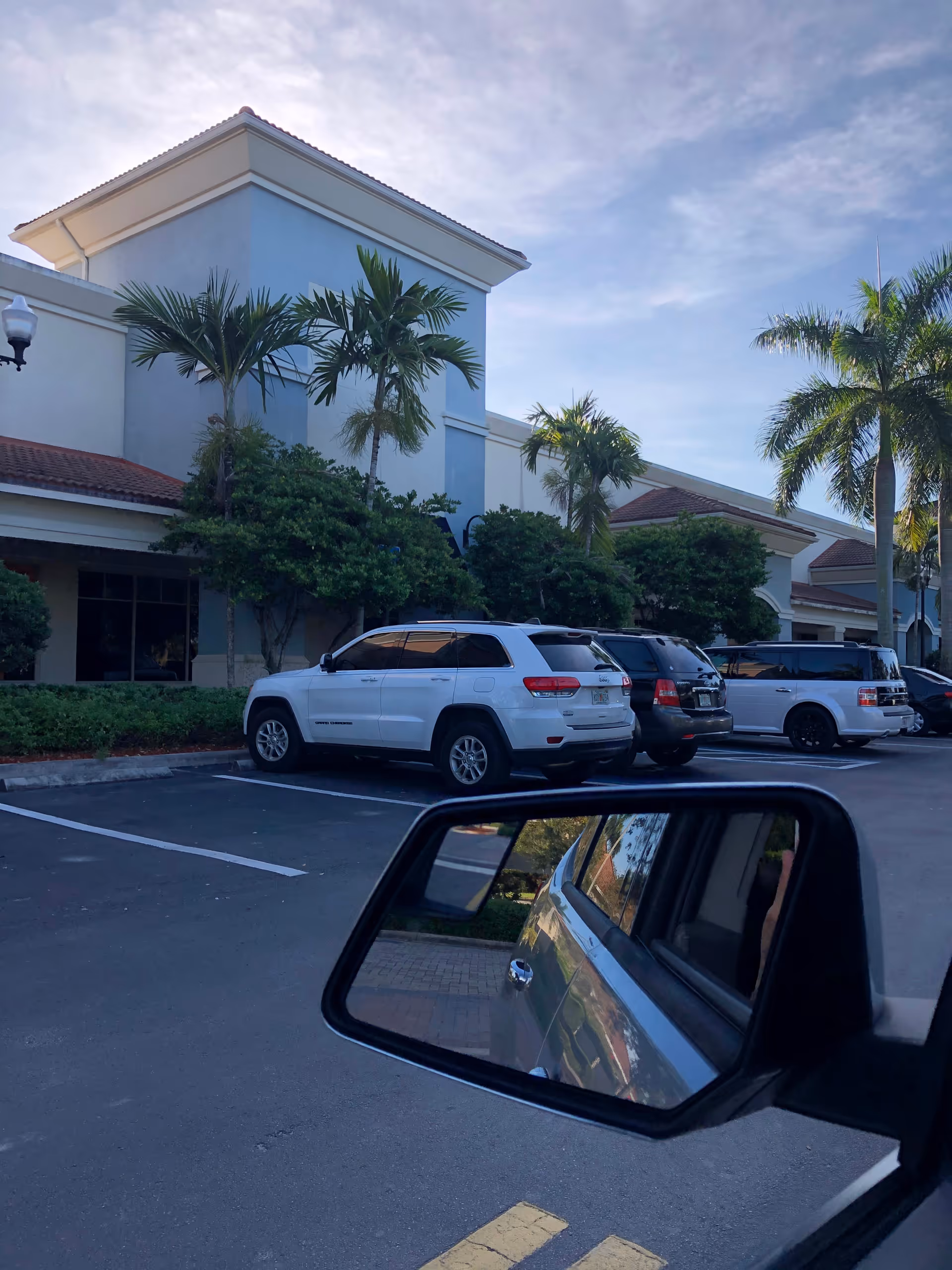 Exterior view of Nicklaus Children's Miramar Outpatient Center with palm trees and parked cars