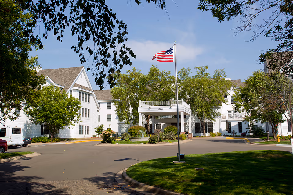 Exterior view of Ecumen Lakeview Commons with flagpole and trees.