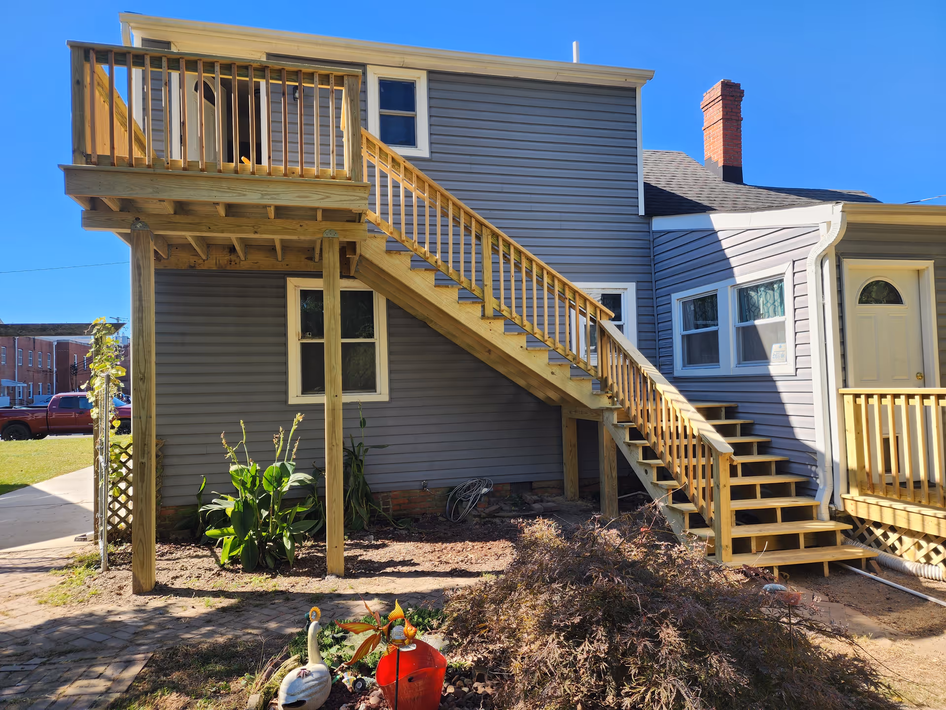 Two-story gray building with wooden exterior stairs and a small garden area.