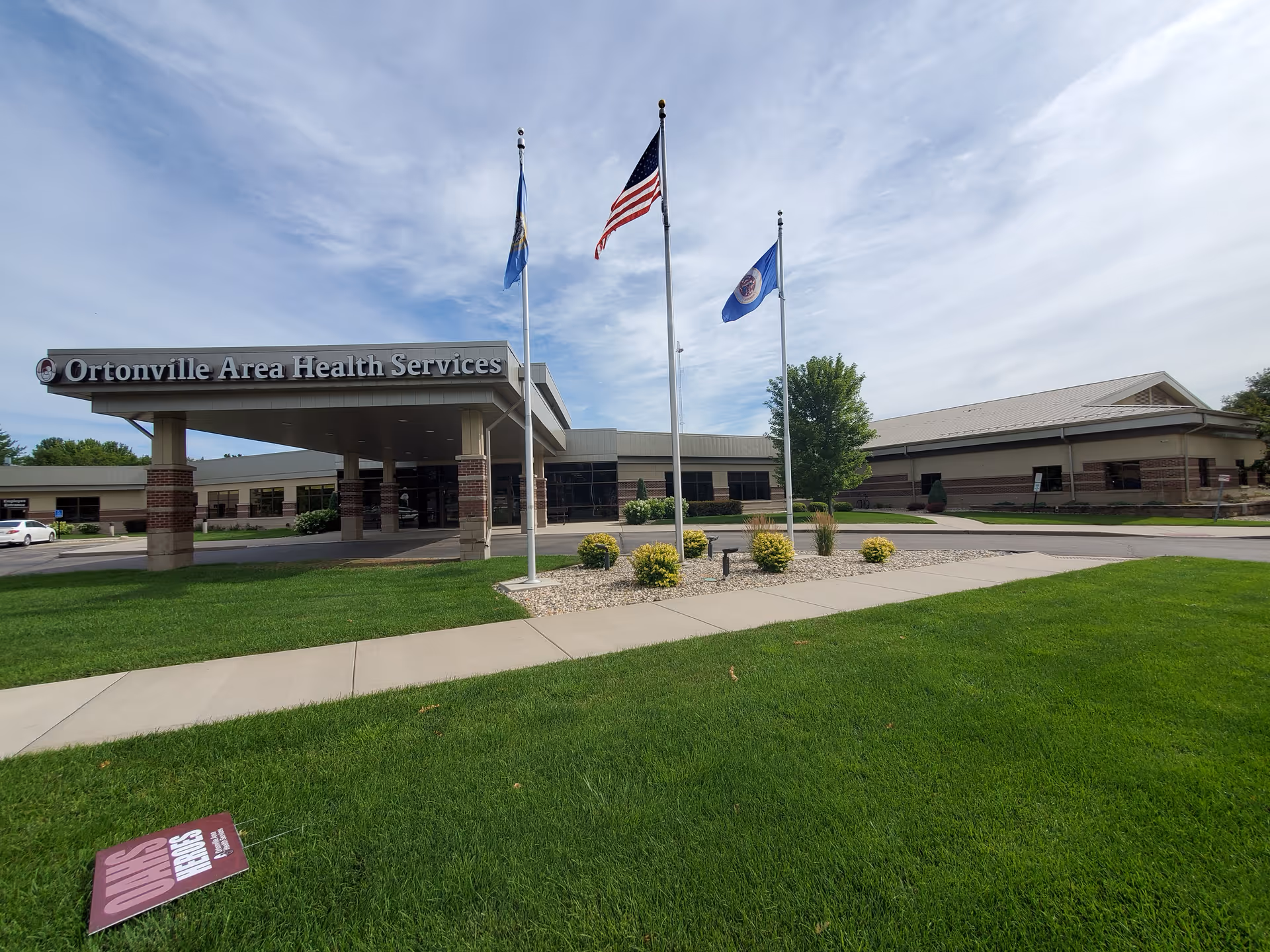 Exterior view of Ortonville Area Health Services entrance with flags and landscaping.