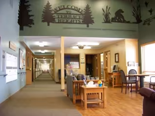 Indoor lounge area with tables, chairs, a hallway, and a 'Welcome to Terrace Heights' mural.