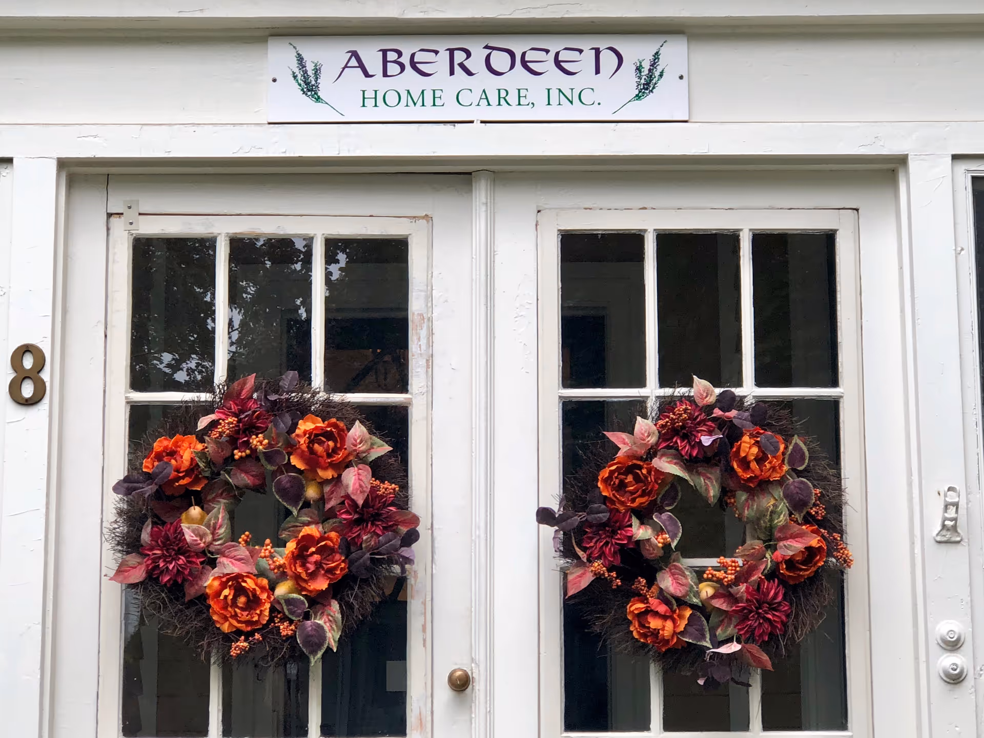 Exterior entrance with white double doors, autumn wreaths, and a sign for Aberdeen Home Care, Inc.
