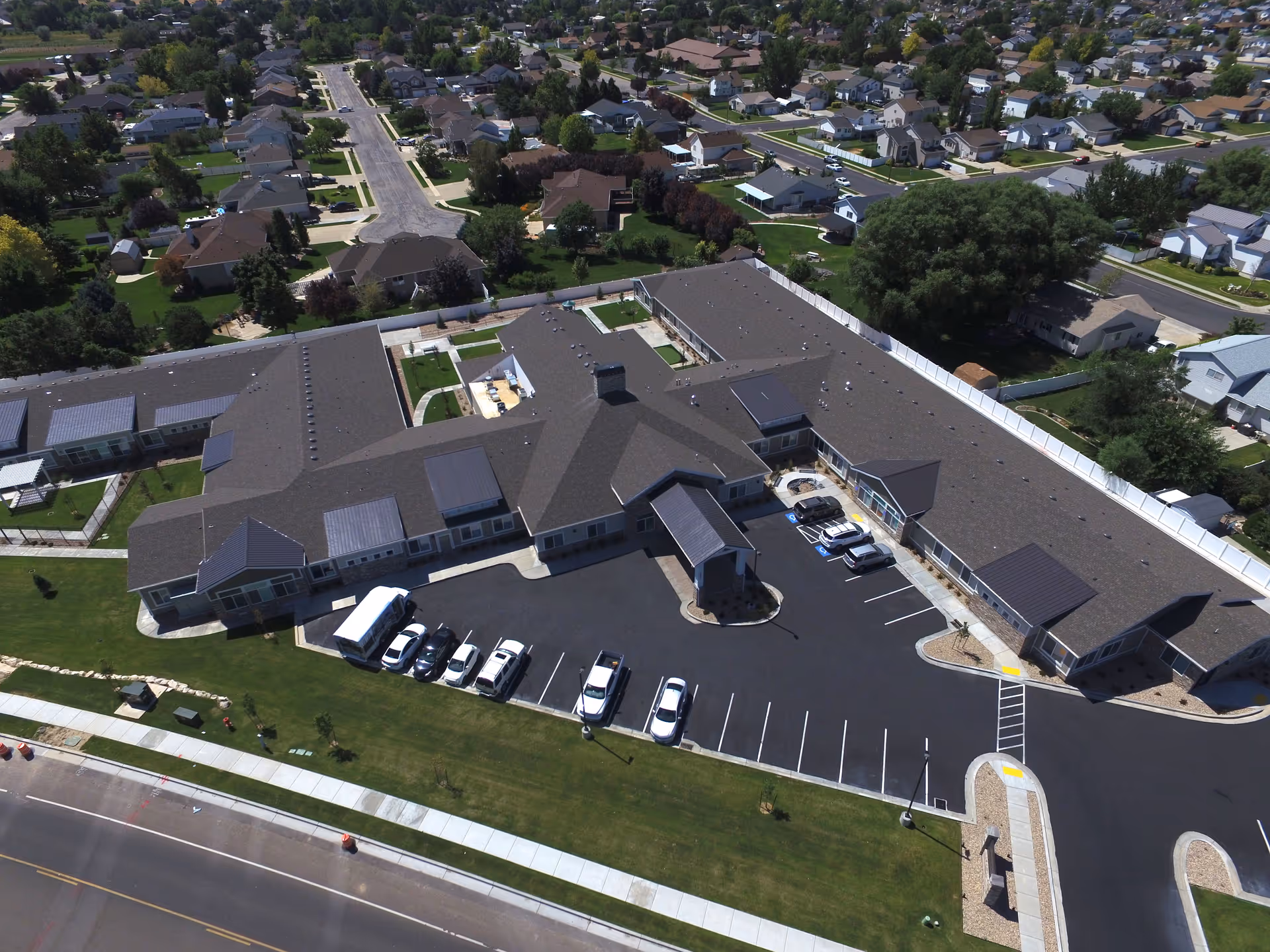 Aerial view of a single-story assisted living facility with a central covered entrance, parking lot, and surrounding residential neighborhood.