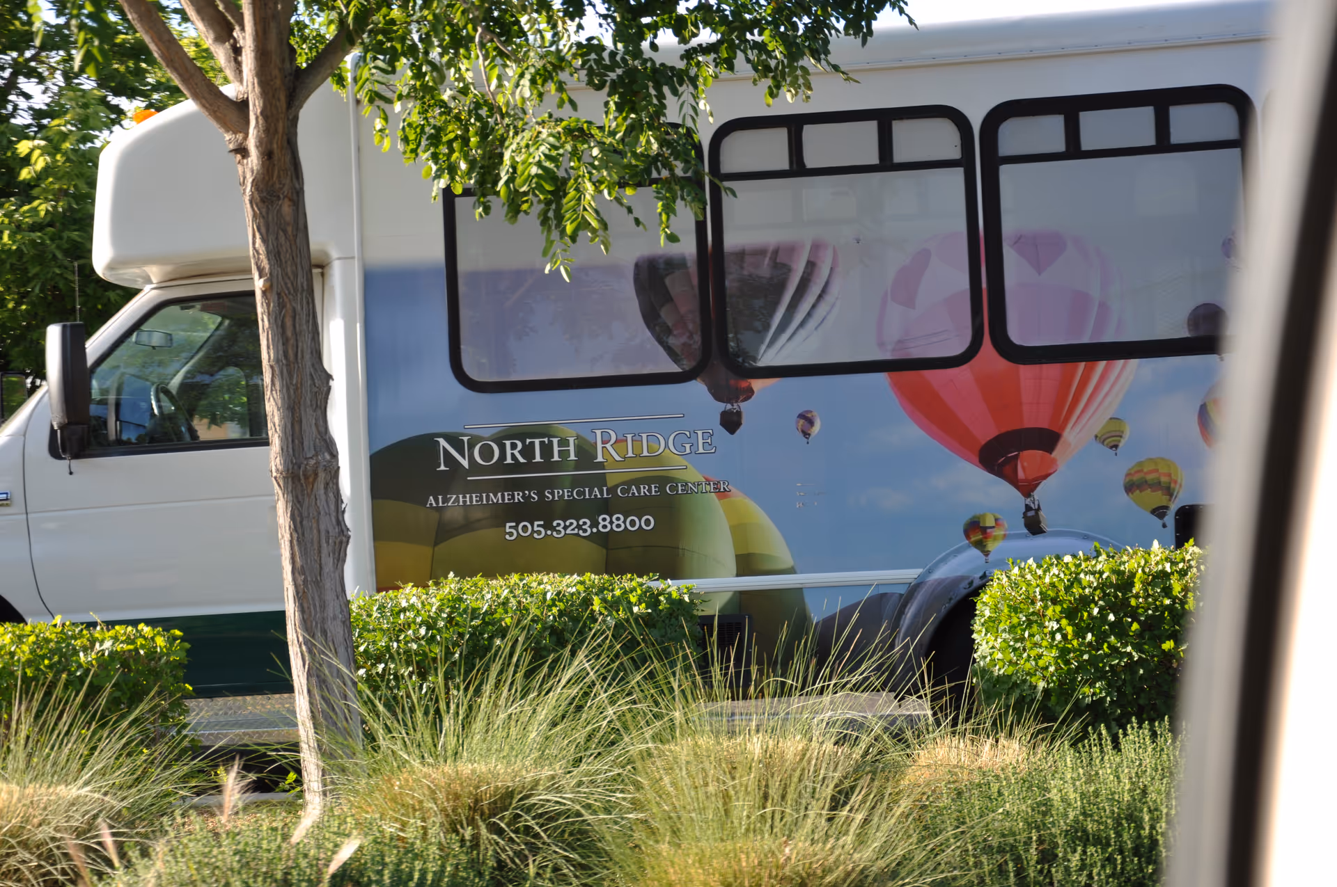 Side of a Morningstar North Ridge shuttle bus parked beside greenery.