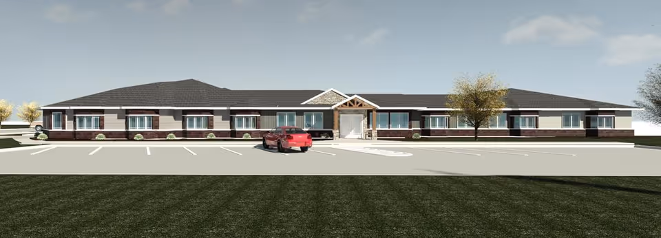 Single-story senior living facility exterior with parking lot and landscaped surroundings.