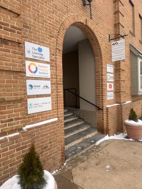 Brick building entrance with archway, signs on the wall, and snow on the ground.