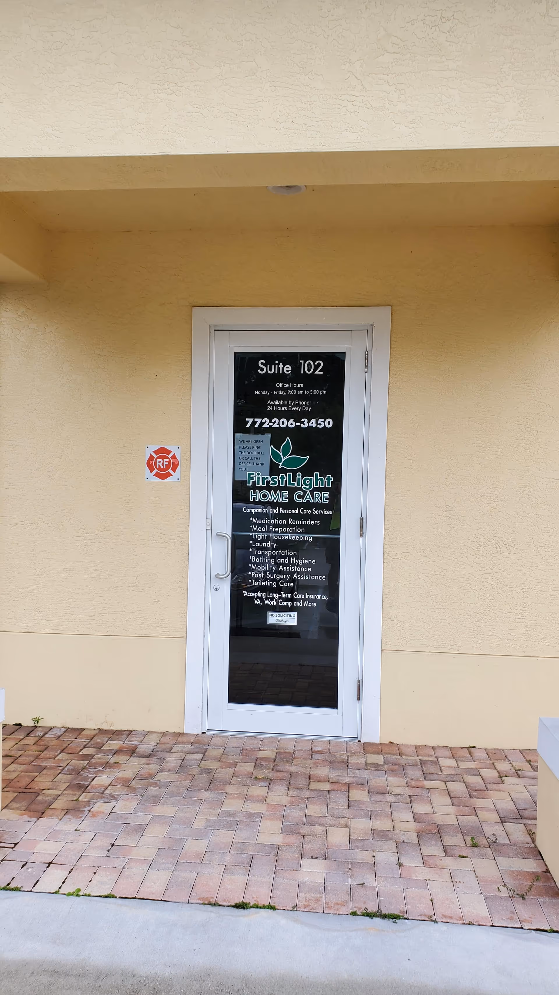 Exterior view of a beige building entrance with a glass door labeled FirstLight Home Care