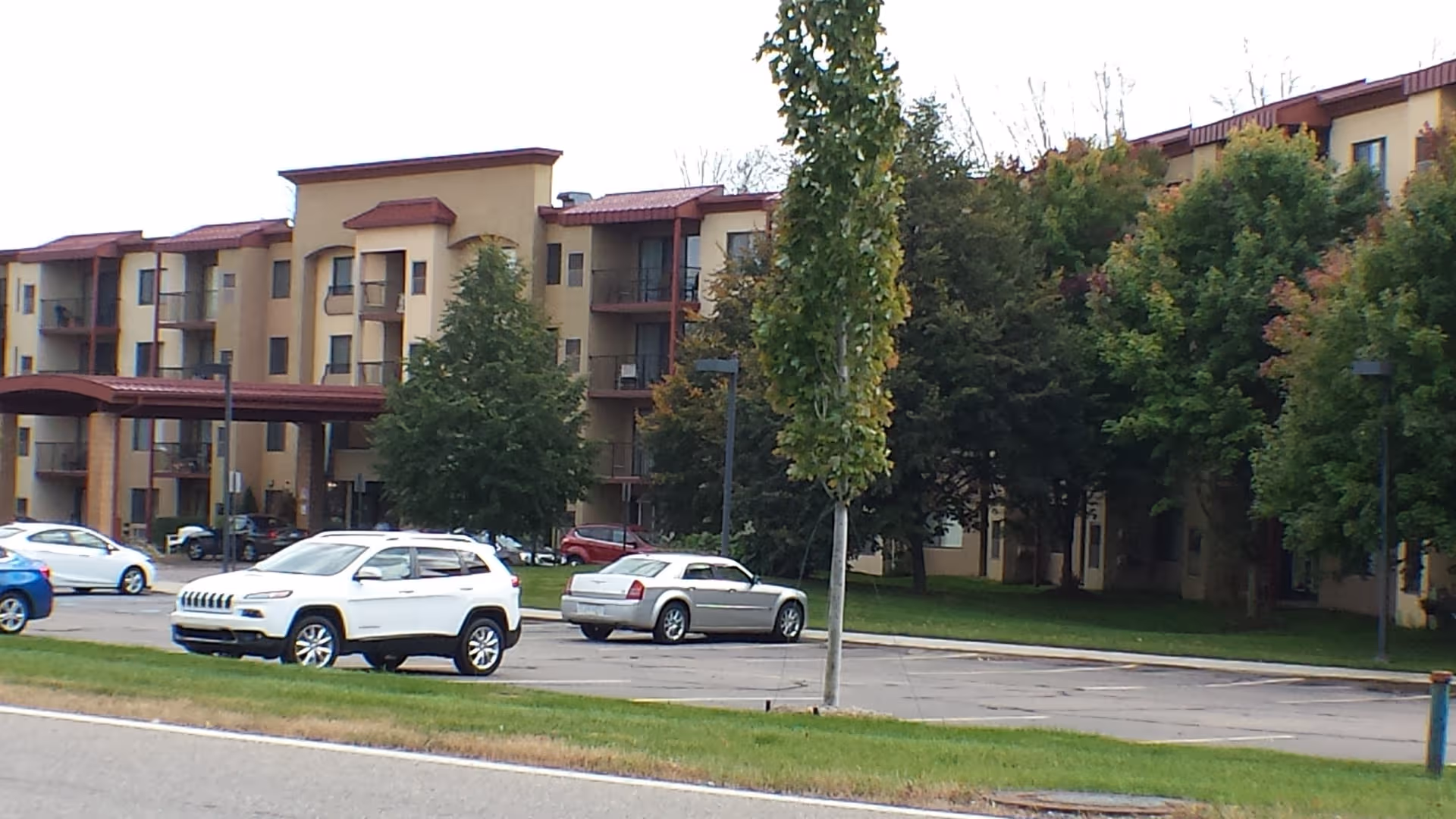 Exterior view of Pine Ridge Villas of Shelby, a multi-story senior living building with parked cars.