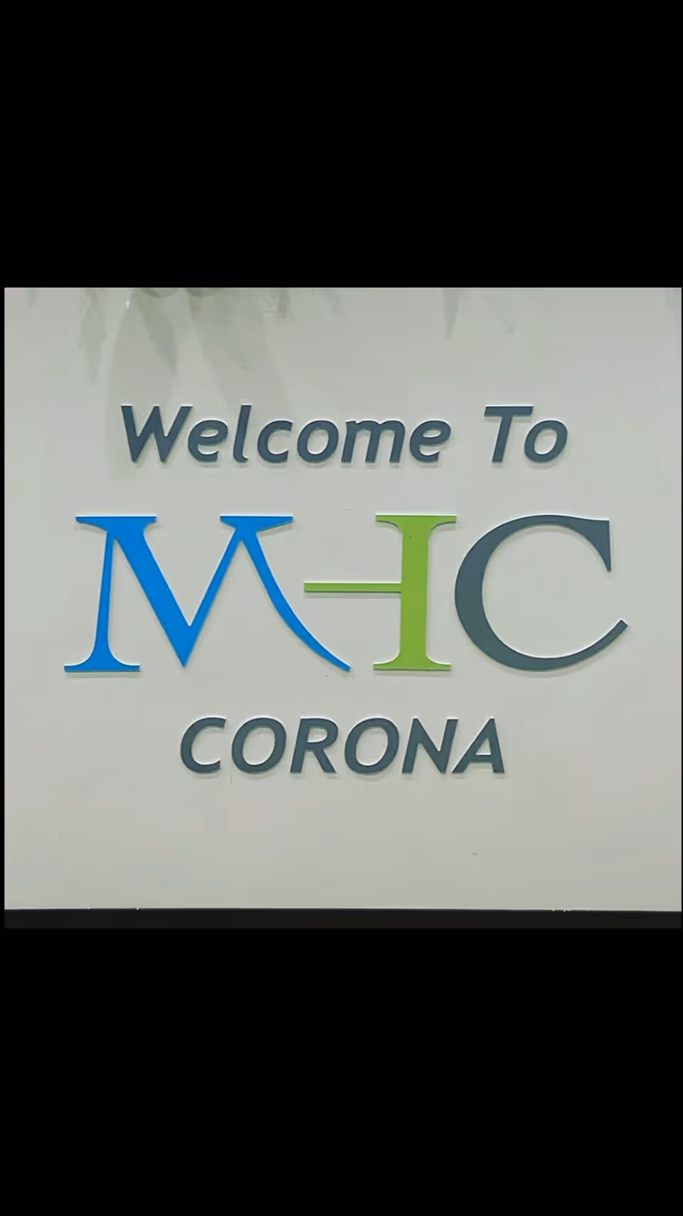 Welcome To MHC Corona sign on a pale wall.
