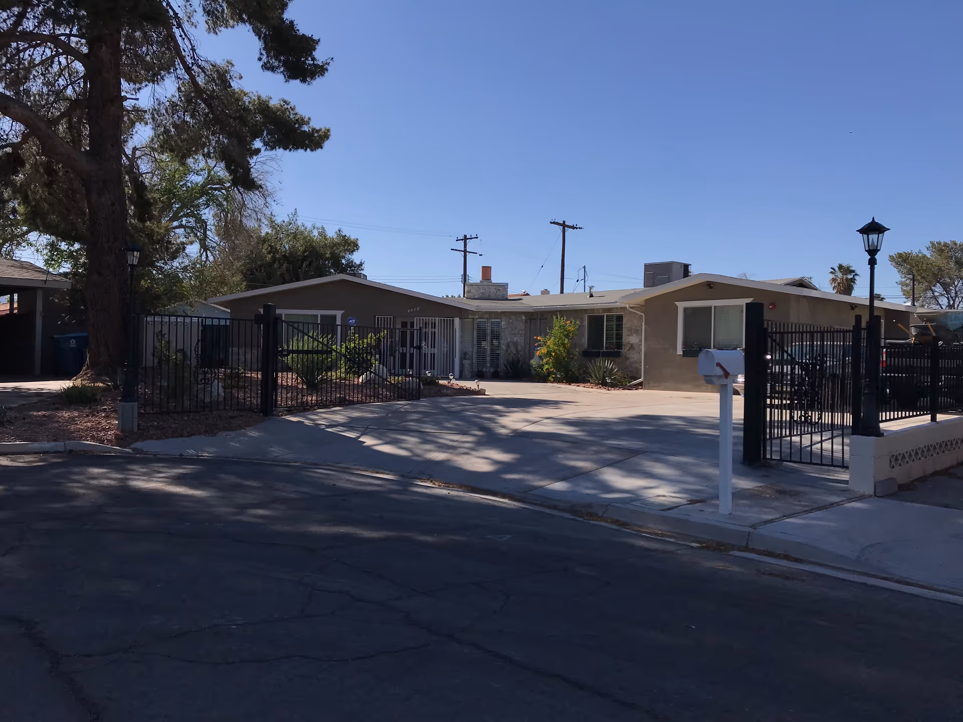 Gated, single-story senior care home front with driveway, mailbox, and landscaping.