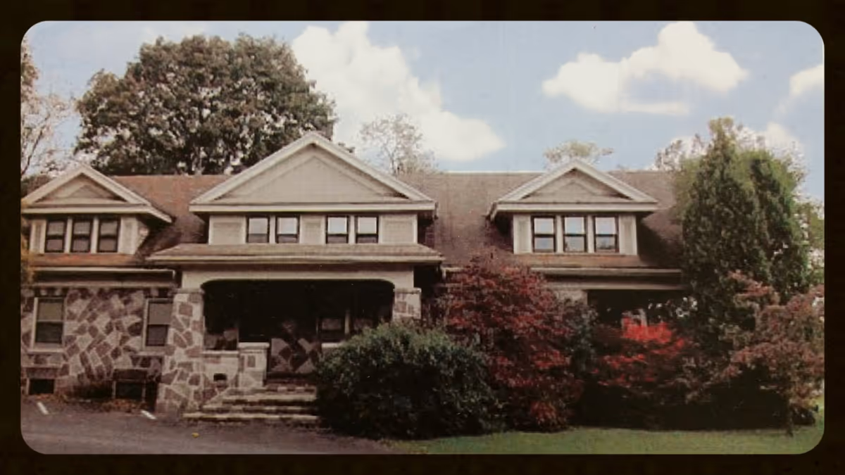 Front view of a stone-and-wood senior-care building with landscaped bushes and trees.