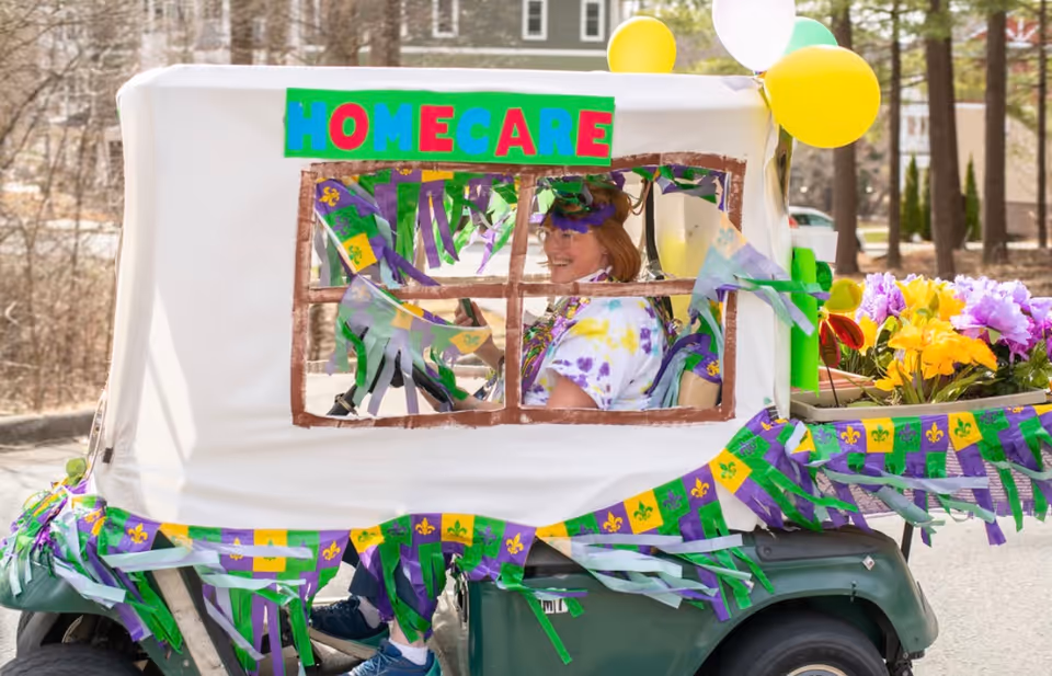 Decorated golf cart with a HOME CARE banner, balloons, and flowers outdoors.