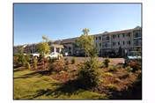 Exterior view of Vintage at Sequim senior living building with landscaped lawn and trees.