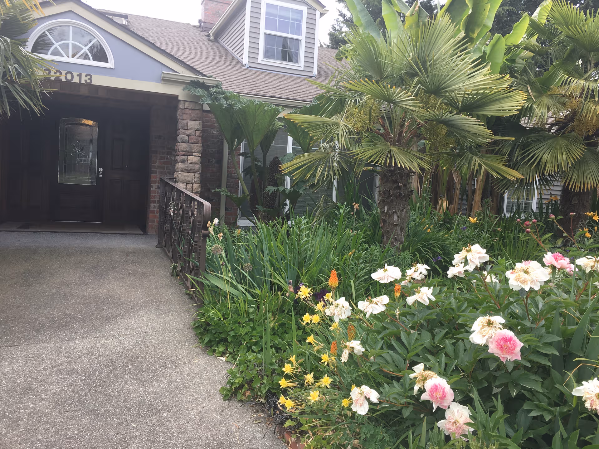 Front entrance of Yitref Adult Family Home with lush garden and palm trees.