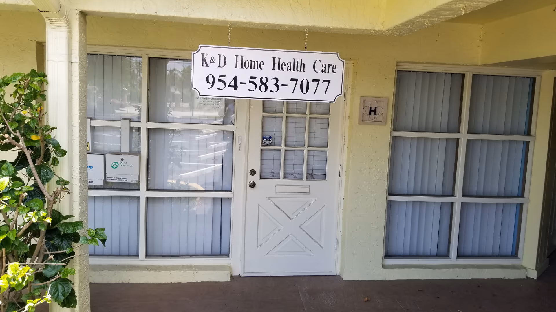 White door flanked by large windows and a sign reading K&D Home Health Care.