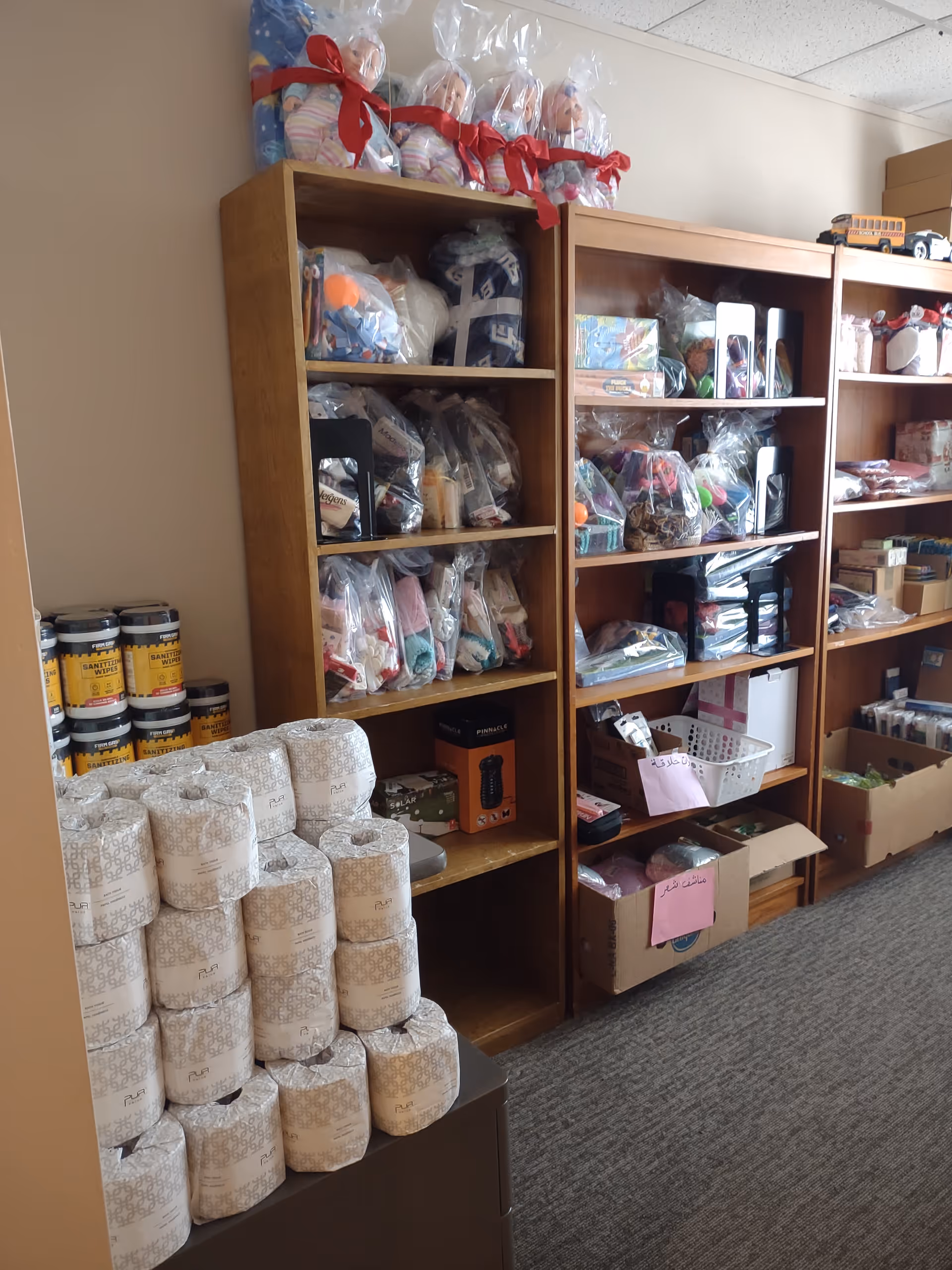 Interior storage area with tall wooden shelves filled with assorted supplies and stacked toilet paper.